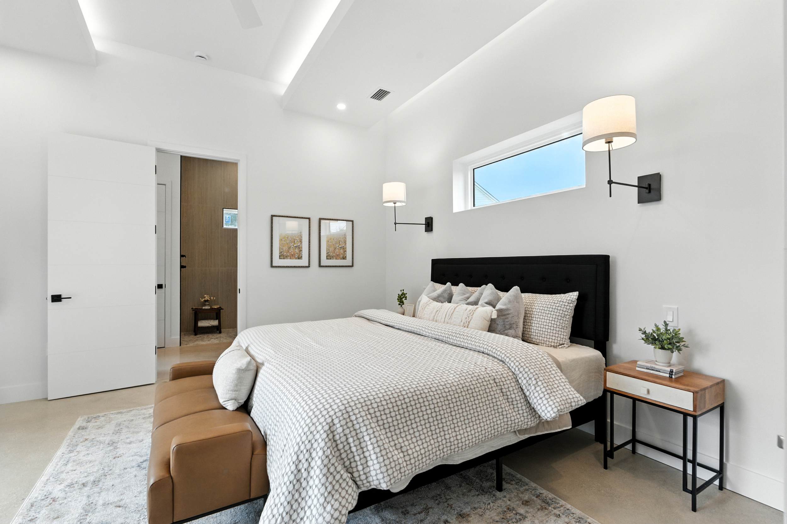 Vacant staging - master bedroom with black tufted headboard and camel leather bench