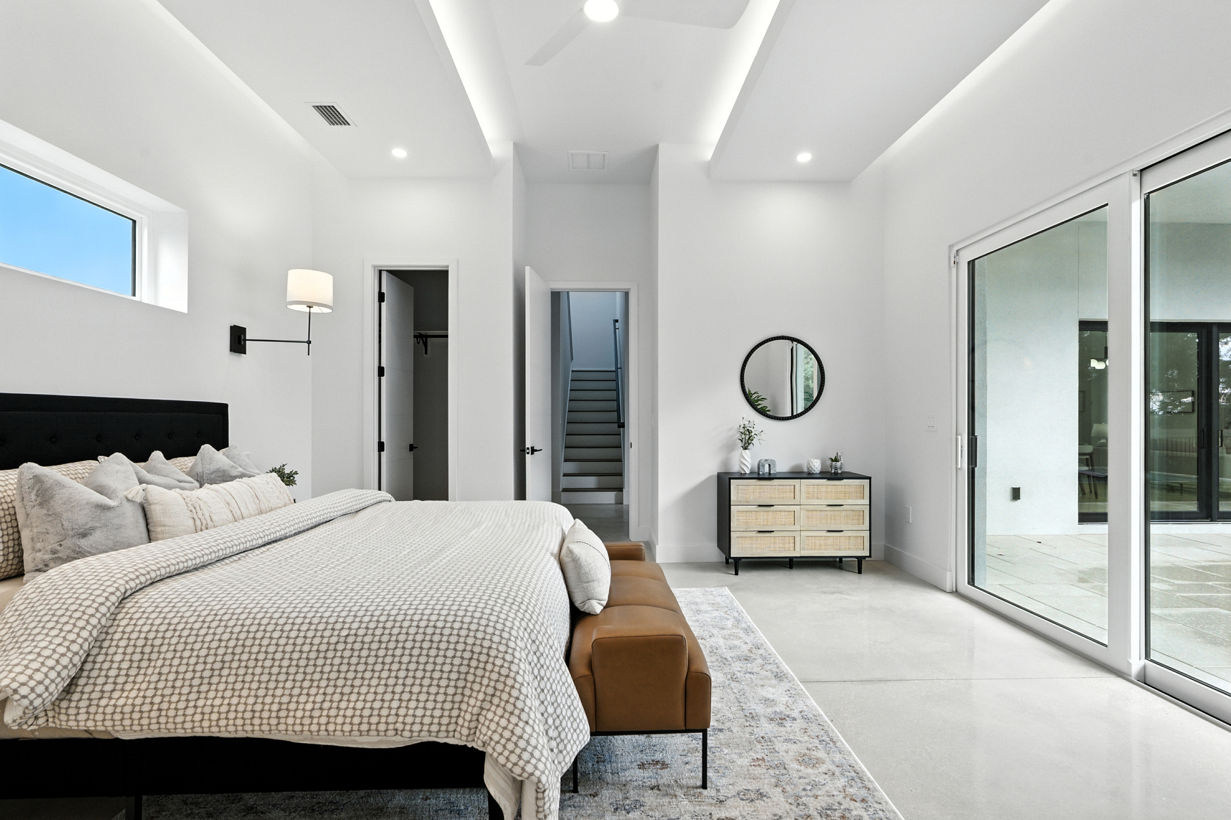 Vacant staging - master bedroom with black upholstered headboard and rattan dresser